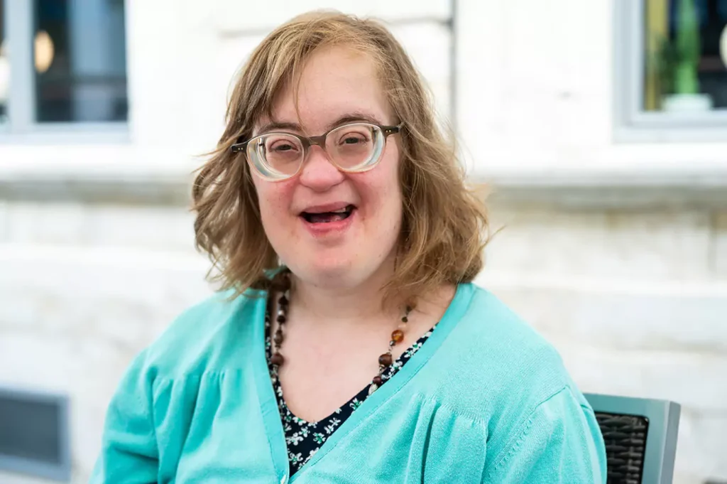 A happy woman with down syndrome sitting at an outdoor bench