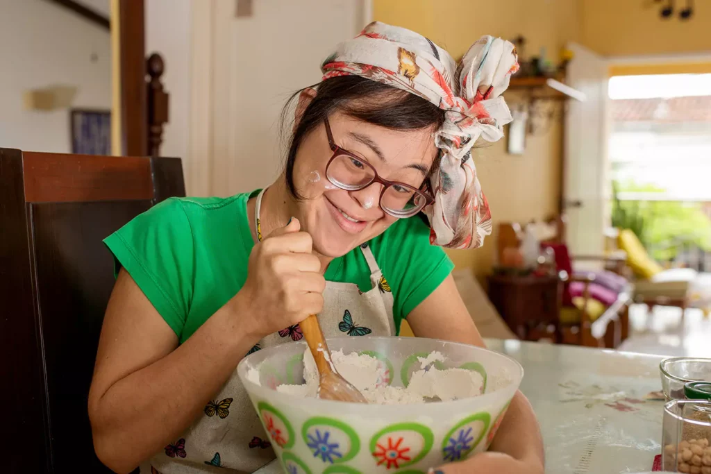 A woman with down syndrome is having fun while baking cookies at home