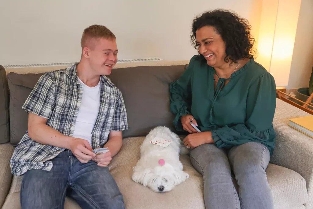 A young disabled man and a In House Holistic Care support worker playing cards together